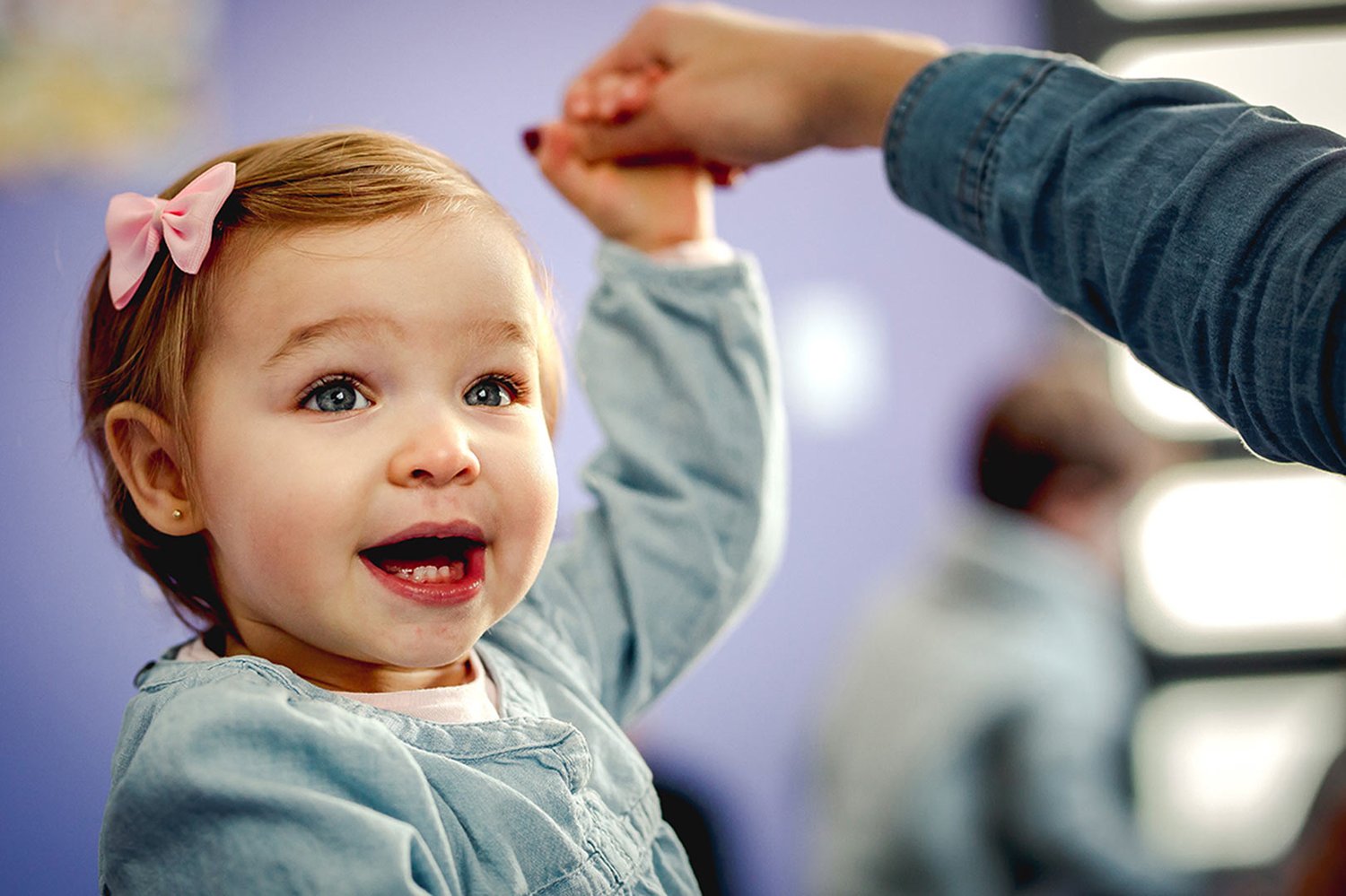 A baby opens her mouth wide in a burst of pure vocalization during class, her whole face alive with the joy of making sound.