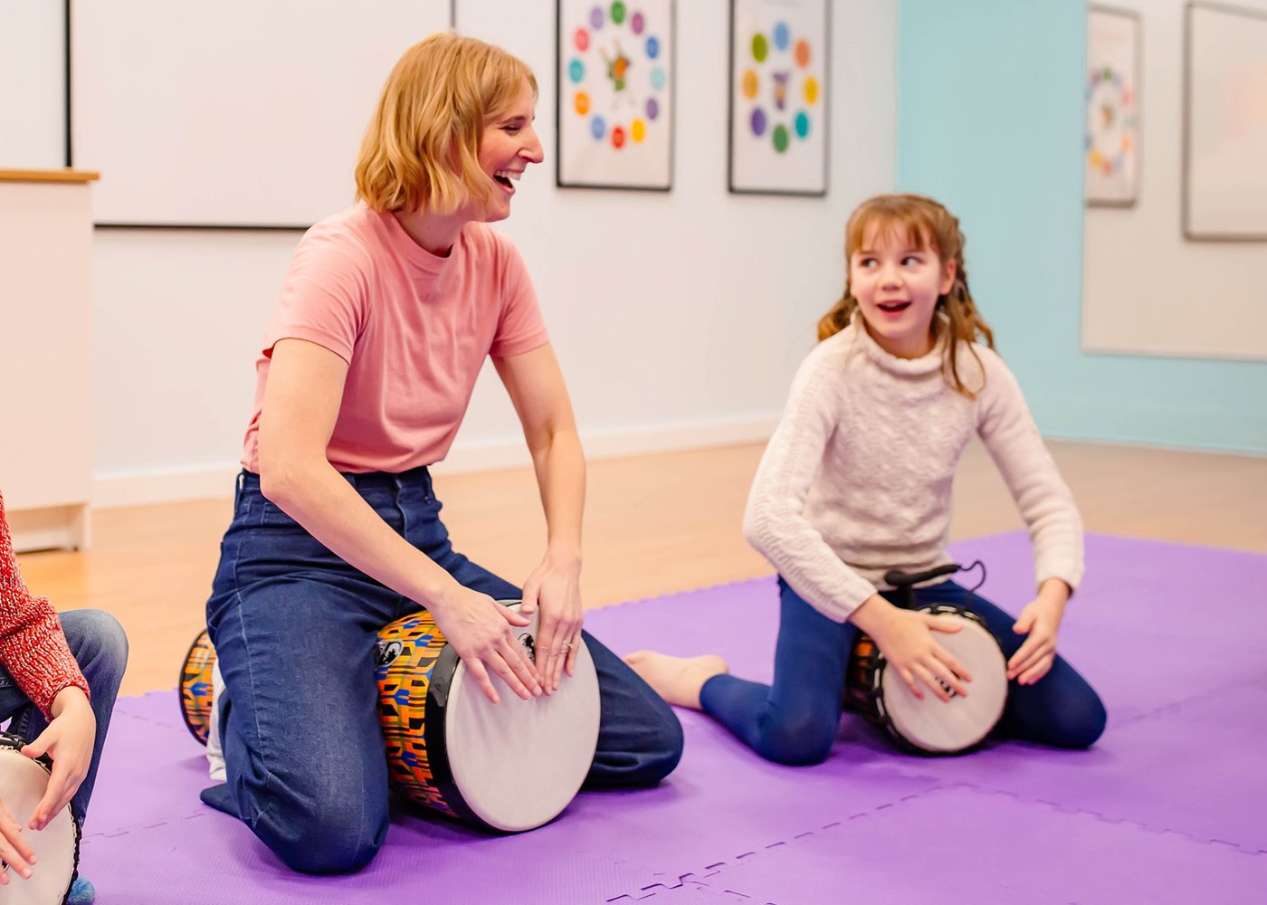 A teacher and child drumming together in a bright East Nashville music studio