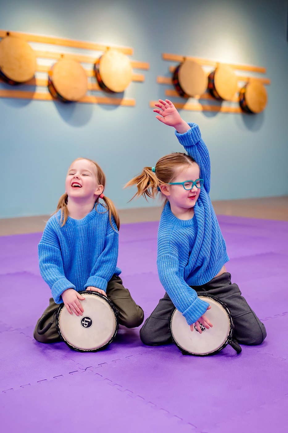 Two kids raising their hands during a drumming game