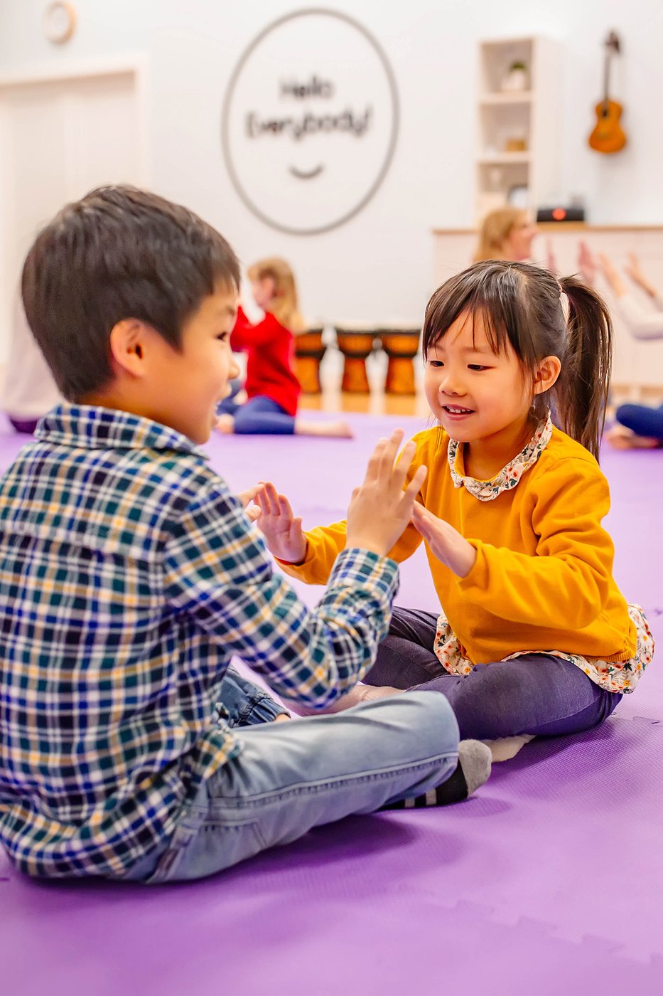 Two early-elementary children playing a hand-clapping rhythm game and laughing