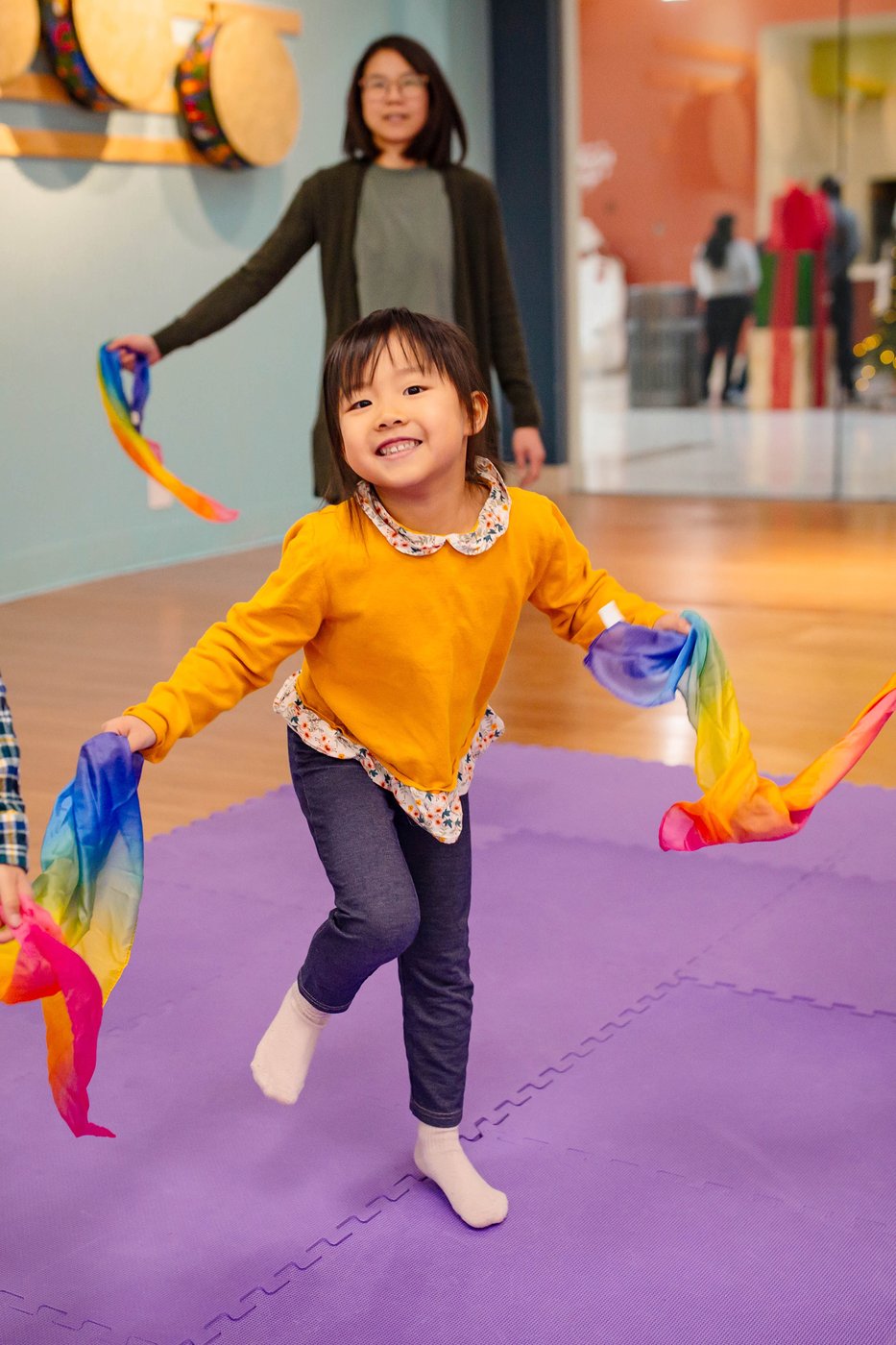A child dancing with a rainbow scarf in a music and movement class